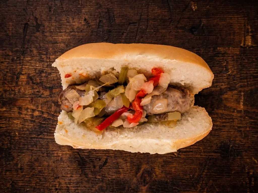 Italian sausage sandwich with peppers and onions on a Mancini's roll